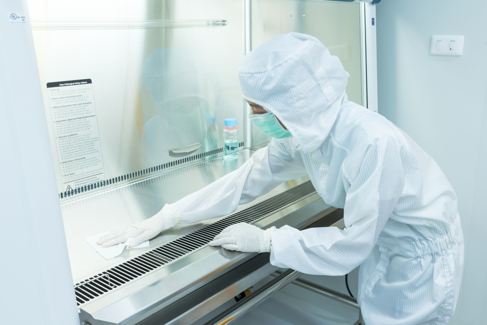 A scientist in sterile coverall gown using alcohol 70% and cleanroom wipes for cleaning Biological safety cabinet (BSC) in laboratory