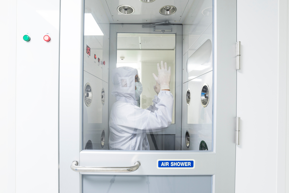 A scientist in sterile coverall gown using air shower to remove particle contamination before going to work area, cleanroom