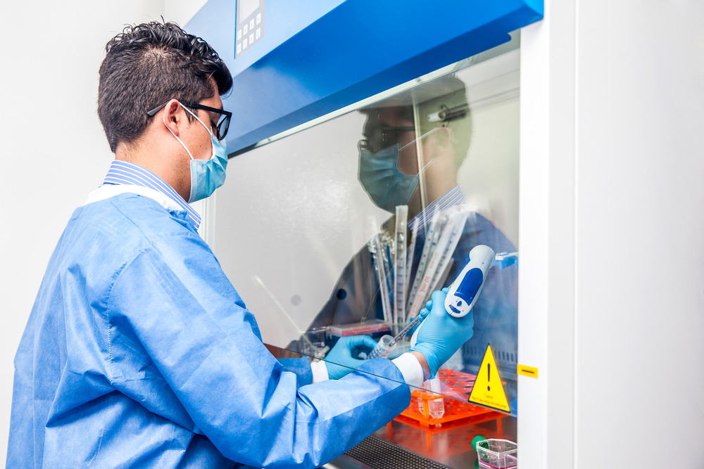 Young scientist working in a safety laminar air flow cabinet at laboratory