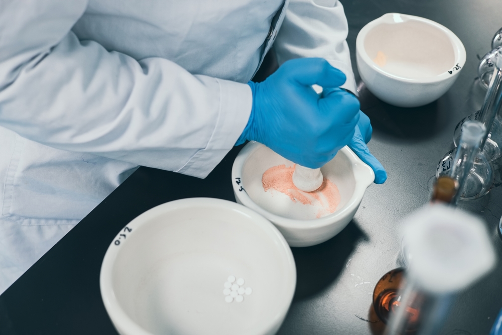 Professional pharmacist grinding a medical preparation using a mortar and pestle