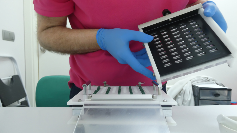 Pharmacist making a capsule of medicine using a manual machine