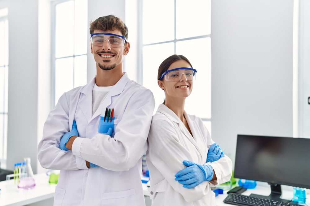 Man and woman partners wearing scientist uniform standing with arms crossed gesture at laboratory